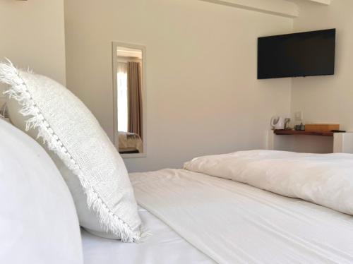 a white bed with white pillows and a flat screen tv at Fiddler's Green in Magoebaskloof