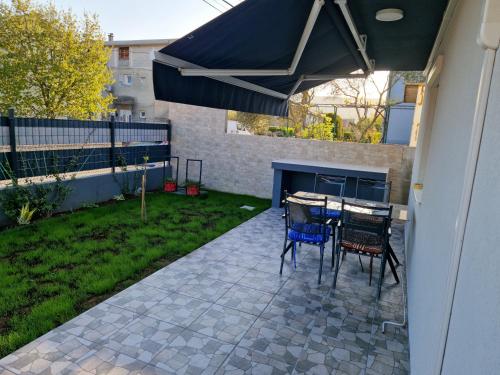 a patio with a table and chairs under an umbrella at Apartman Pranić Mostar in Mostar