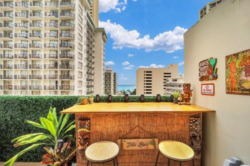 a balcony with a table and two chairs and a building at Surf & Sip Ocean View Tiki Style in Honolulu