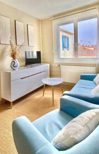 Cette chambre comprend deux lits, une table et un canapé. dans l'établissement Maison Richet, à Les Sables-dʼOlonne