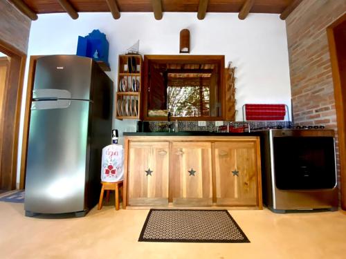 a kitchen with a stainless steel refrigerator and wooden cabinets at Vila Pitanga - Arandis in Marau
