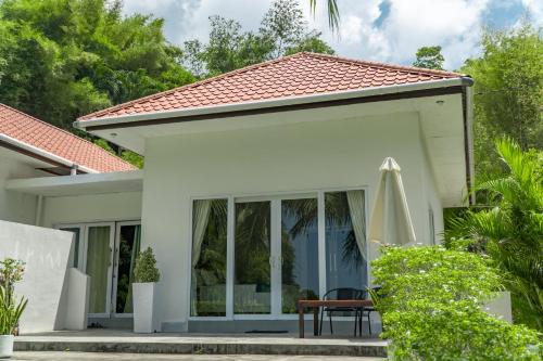 a white house with a table and a umbrella at The Hawk's Nest Resort in Sabong