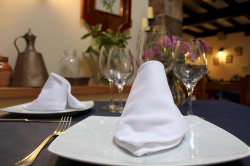 a table with two plates with napkins and wine glasses at Posada Ormas in Ormas