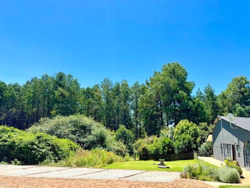 a house with a garden and trees in the background at Fiddler's Green in Magoebaskloof