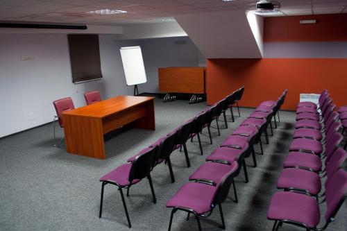 a conference room with purple chairs and a podium at Optima Collection Kharkiv Hotel in Kharkiv