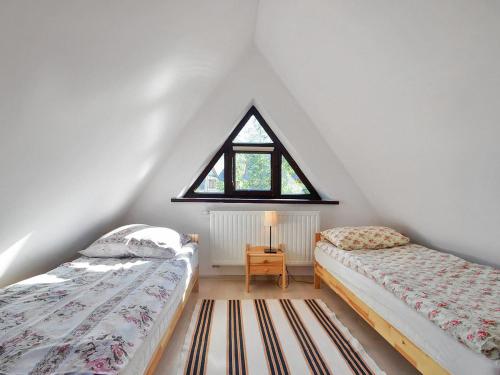 ザコパネにあるDomek Wiktorのベッド2台と窓が備わる屋根裏部屋です。