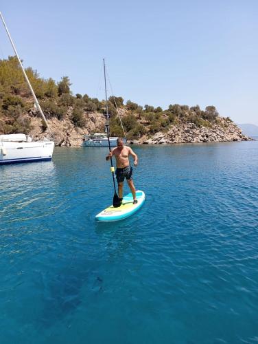 a man holding a pole on a paddle board in the water at Yacht-Urlaub in den Buchten von Datca in Datca