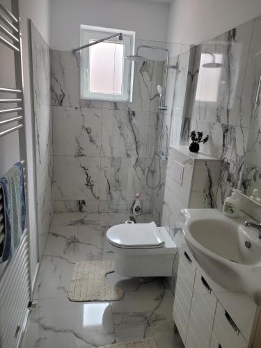 a white bathroom with a toilet and a sink at La matusa in Sibiu