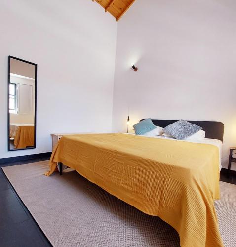a bedroom with a large bed with a yellow blanket at Casa do Beco in Angra do Heroísmo