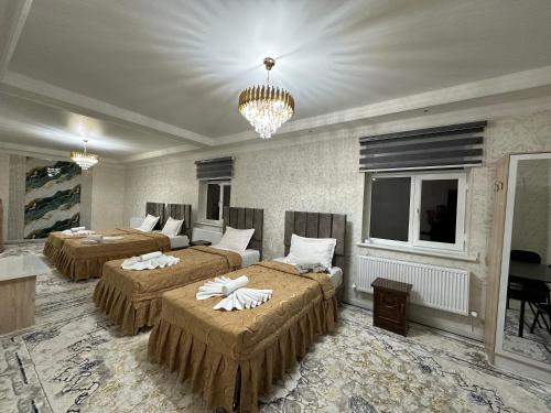 a hotel room with three beds and a chandelier at Guest House Bekturdi in Khiva