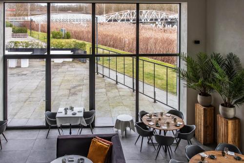 a restaurant with tables and chairs and large windows at De Koolputten in Waasmunster