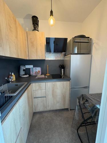 une cuisine avec des armoires en bois et un réfrigérateur dans l'établissement Appartement proche de la plage, à Argelès-sur-Mer