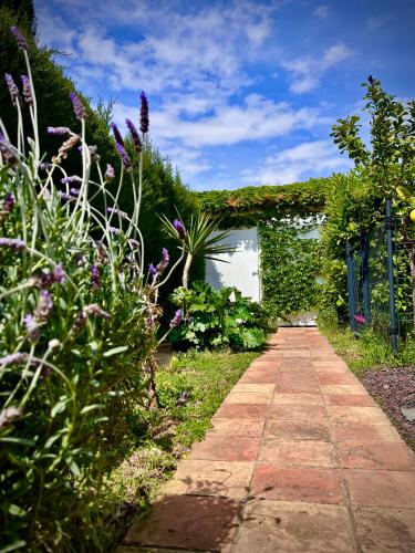 a walkway in a garden with plants and flowers at Sitges Garden Suite in Sitges