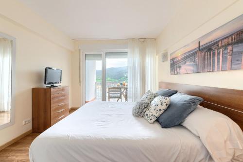 a bedroom with a large bed with a tv on the wall at Coast & Beach View Parking in Bakio
