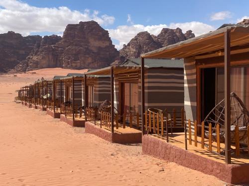 a row of houses in the desert with mountains in the background at Wadi Rum Santa Camp in Wadi Rum