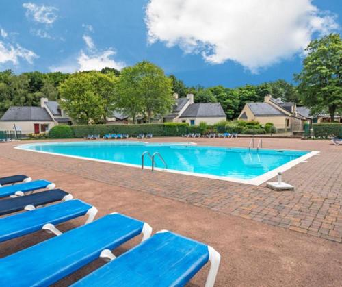 - une piscine avec des chaises longues bleues dans la cour dans l'établissement cottage cosy du golf avec piscine, à Ploemel