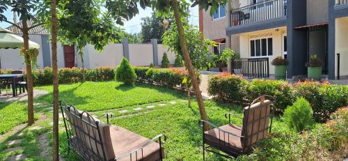 two benches sitting in the grass in a garden at Oreville Apartments in Goma