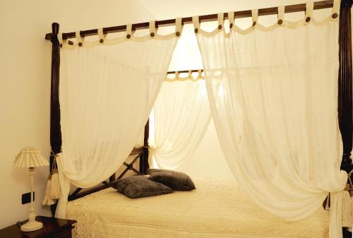 a bedroom with a canopy bed with white curtains at Willaria Country House in Cursi
