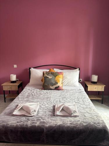 a bed with two pillows on it with a pink wall at FIGALIA Apartments in Kavala