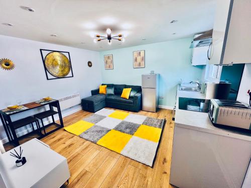 a living room with a couch and a kitchen at Luxury 1B Chalet wt free parking nr LTN Airport, L&D Hosp, Whipsnade Zoo, fast trains to Central London in Luton