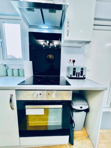 a small kitchen with a stove and a sink at Luxury 1B Chalet wt free parking nr LTN Airport, L&D Hosp, Whipsnade Zoo, fast trains to Central London in Luton