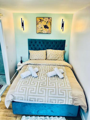 a bedroom with a blue and white bed with two pillows at Luxury 1B Chalet wt free parking nr LTN Airport, L&D Hosp, Whipsnade Zoo, fast trains to Central London in Luton