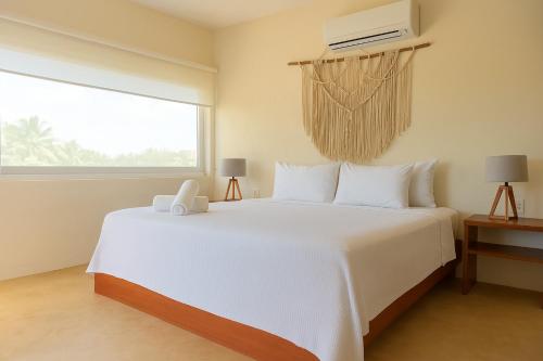 a bedroom with a large white bed and a window at Shankara Holbox in Holbox Island