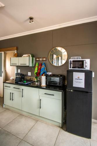 a kitchen with white cabinets and a sink and a mirror at Long Beach Selfcatering Namibia in Langstrand