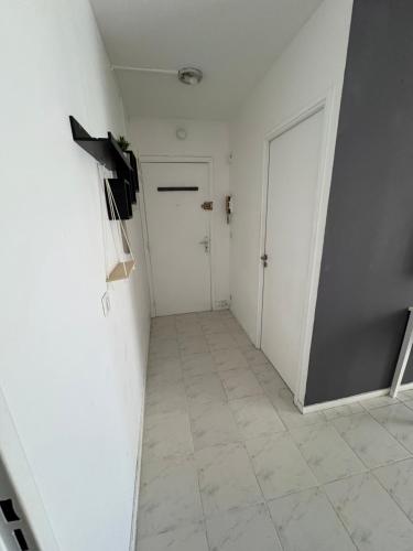 un couloir avec des murs blancs, une porte et du carrelage. dans l'établissement Appartement bord de mer, à Nice