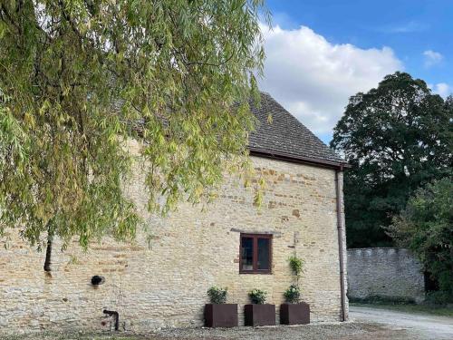 a brick building with a window and a tree at Highend Cotswold Barn near Soho Farmhouse & Daylesford in Duns Tew