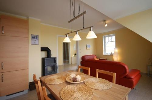 a living room with a table and a red couch at Achtern Diek - Ferienwohnungen in Börgerende-Rethwisch