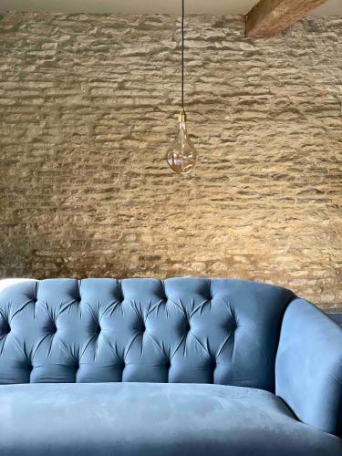 a blue couch in front of a brick wall at Highend Cotswold Barn near Soho Farmhouse & Daylesford in Duns Tew