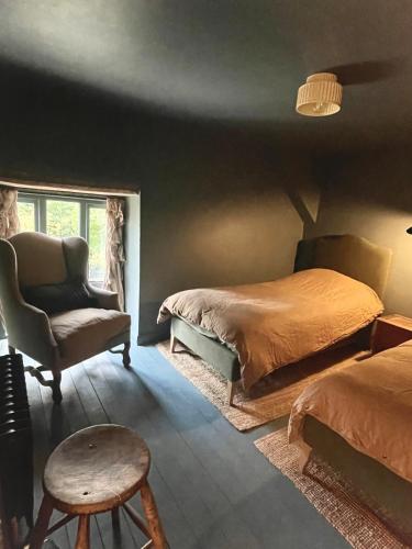 a bedroom with two beds and a chair at Highend Cotswold Barn near Soho Farmhouse & Daylesford in Duns Tew