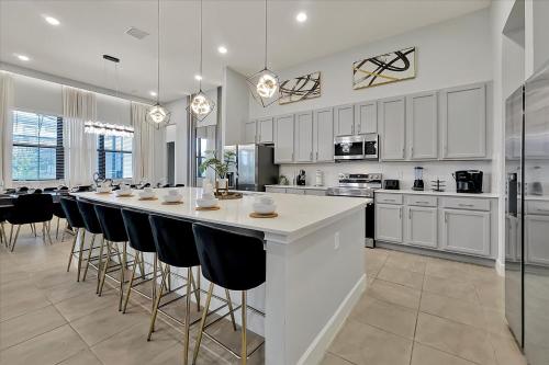 a large kitchen with a long bar with bar stools at Epic Orlando Mansion-Pool-Game Room-Theater-2 in Orlando