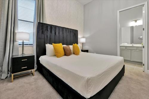 a bedroom with a large white bed with yellow pillows at Epic Orlando Mansion-Pool-Game Room-Theater-2 in Orlando