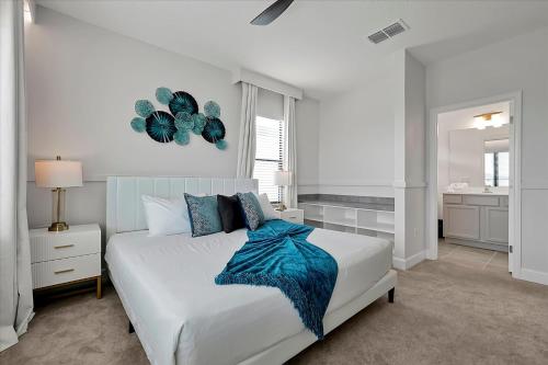 a bedroom with a white bed with a blue blanket on it at Epic Orlando Mansion-Pool-Game Room-Theater-2 in Orlando
