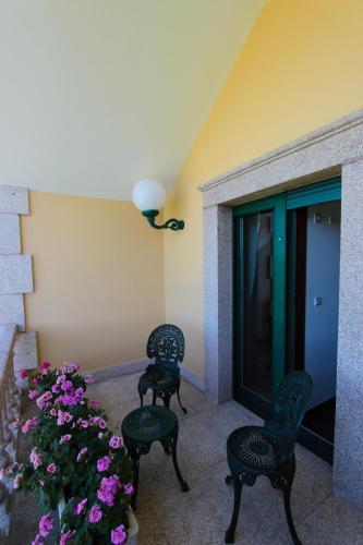 a patio with two chairs and a plant with purple flowers at Villa Pérez Rey in Dumbría