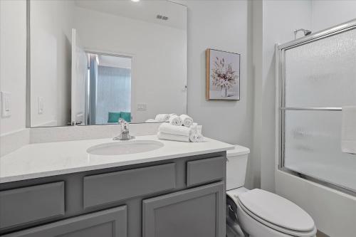a white bathroom with a sink and a toilet at Epic Orlando Mansion-Pool-Game Room-Theater-2 in Orlando