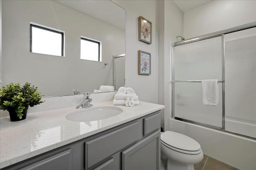 a white bathroom with a toilet and a sink at Epic Orlando Mansion-Pool-Game Room-Theater-2 in Orlando