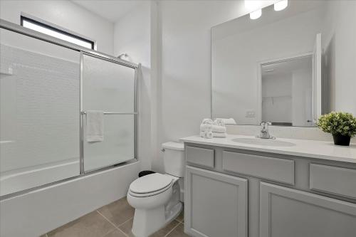 a white bathroom with a toilet and a sink at Epic Orlando Mansion-Pool-Game Room-Theater-2 in Orlando