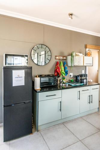 a kitchen with white cabinets and a black refrigerator at Long Beach Selfcatering Namibia in Langstrand