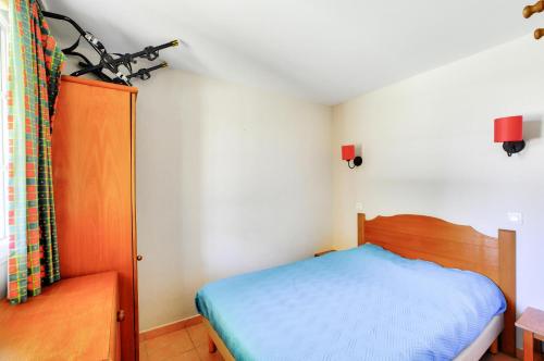 une petite chambre avec un lit et une chaise dans l'établissement La résidence du Lac - maeva Home - Appartement 2 pièces 4 personnes - Sélection MAE-5611, à Monflanquin