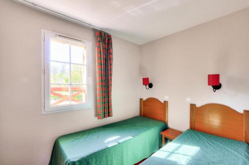 deux lits jumeaux dans une chambre avec fenêtre dans l'établissement La résidence du Lac - maeva Home - Maison 3 pièces 6 personnes - Sélection MAE-4081, à Monflanquin