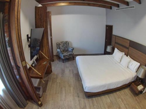 a bedroom with a bed and a chair and a mirror at Hotel Diana in Puebla