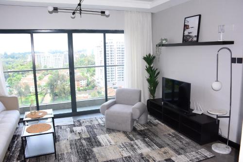 a living room with a couch chair and a television at 2BR WiFi pool gym free breakfast Westlands nairobi in Nairobi