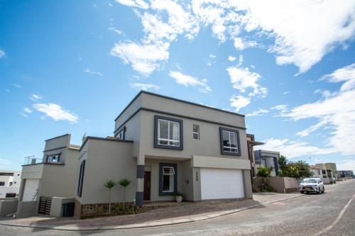 a house on a street with a cloudy sky at Long Beach Selfcatering Namibia in Langstrand