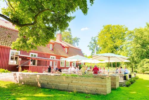 a group of people sitting at tables outside of a red barn at Mötesplats Borstahusen in Landskrona