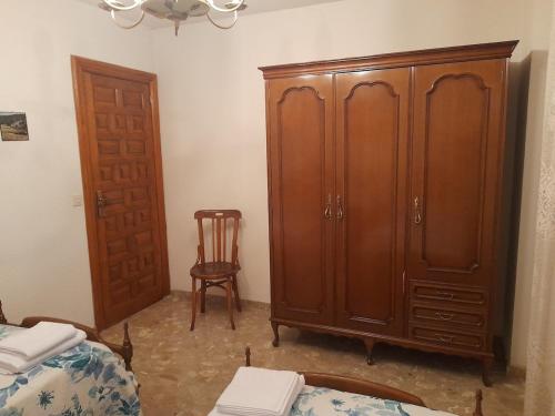 a bedroom with a wooden cabinet and a chair at La casa del Alamo in Vinuesa
