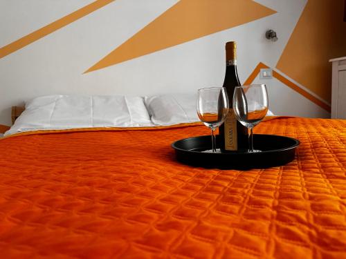 a bottle of wine and two glasses on a bed at Coro & Bentu in Alghero