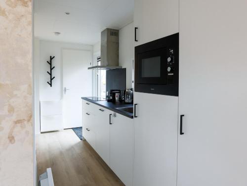 a kitchen with white cabinets and a microwave at Boshuisje - Bos en Bliss in Haarle